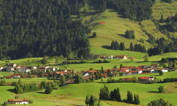 Landschaftsaufnahme vom Allgäu mit grünen Wiesen, Wäldern und einem Dorf